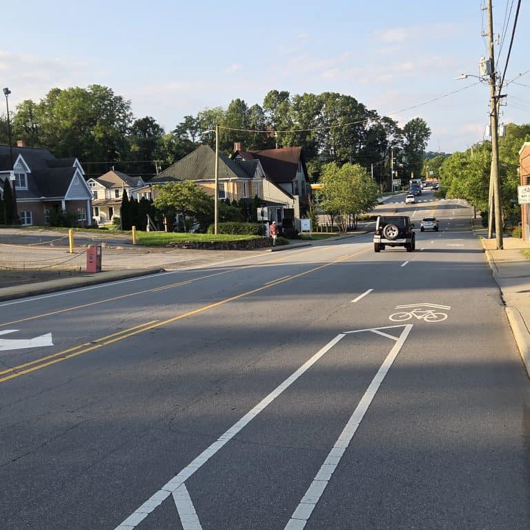 A buffered lane flowing into a shared lane. Shared lane symbol "Sharrow" a bike symbol with arrows as a lane marking. Along Charlotte Street in Asheville