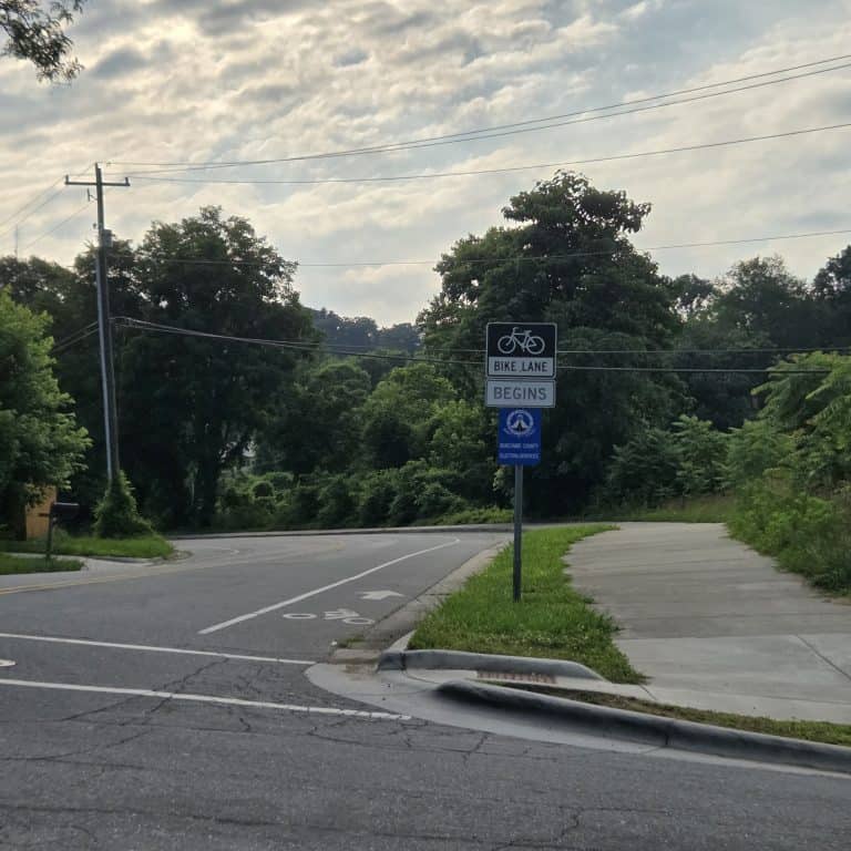 A standard bike lane on Choctaw Street near French Broad Avenue. A Bike lane begins street sign in grass alongside.
