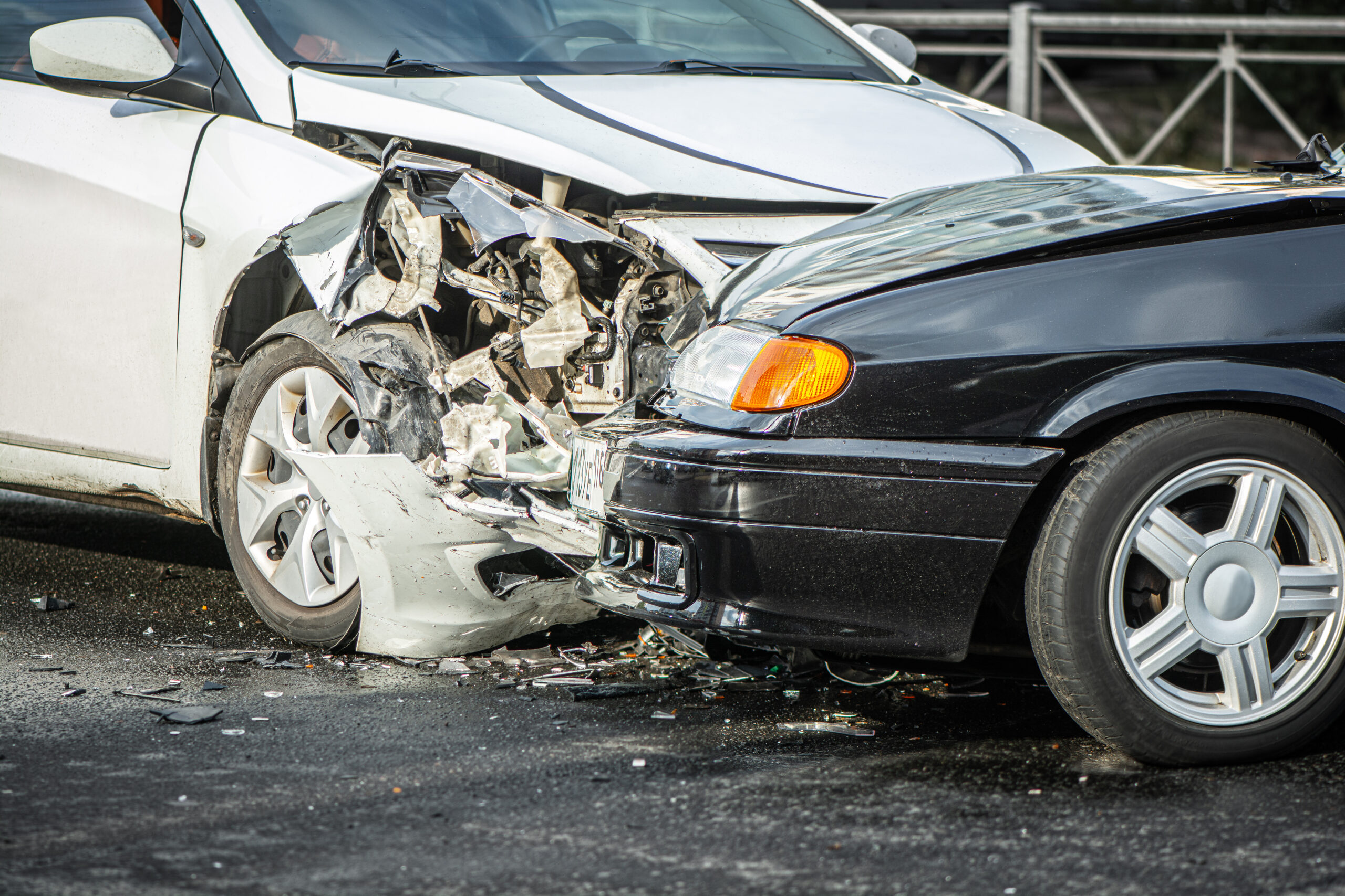 A white and a black car with front-end damage after a head-on collision